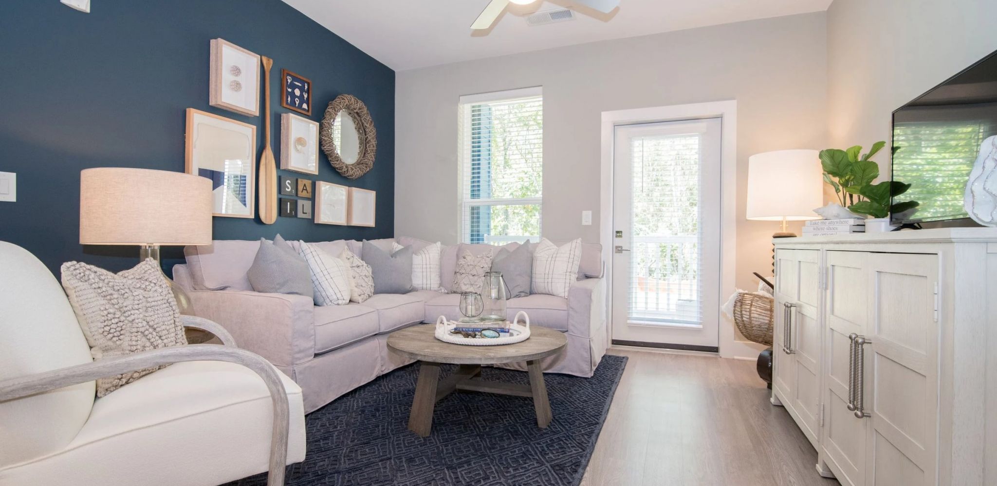 Hawthorne at Indy West apartment living room with ceiling fan, hardwood floors, and a blue accent wall
